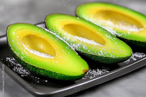 Avocado halves arranged on a plate with a sprinkle of salt, ready to enjoy as a healthy snack