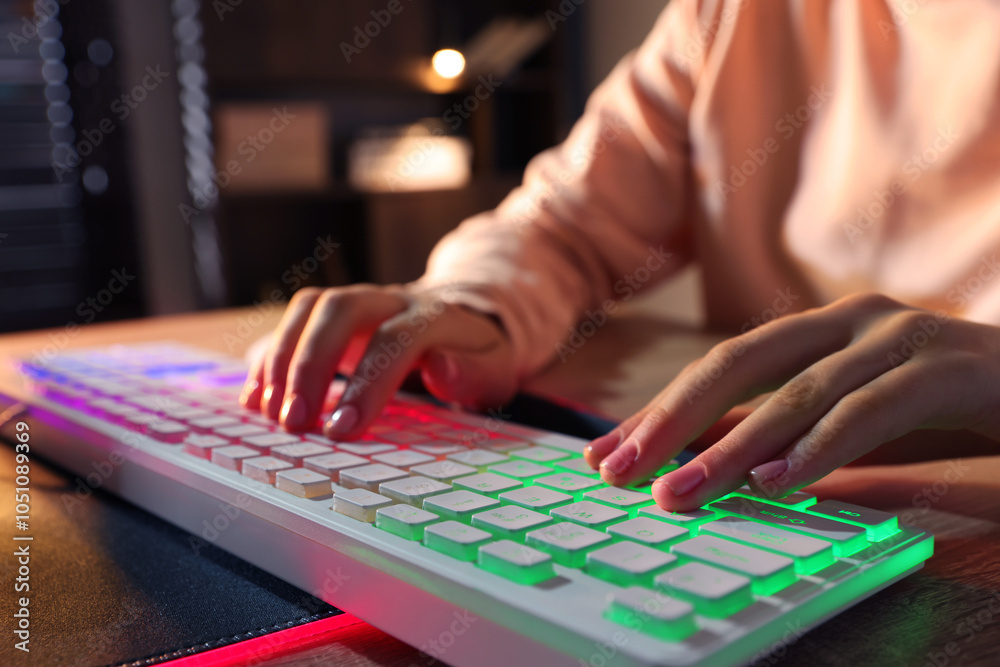 Fototapeta premium Girl using computer keyboard at wooden table indoors, closeup