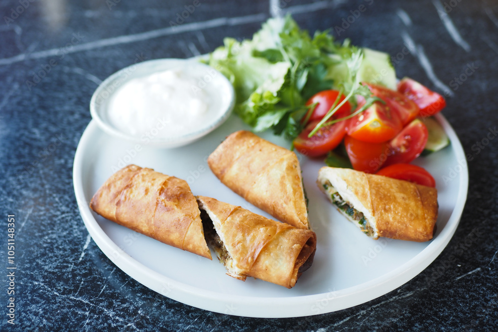 Enjoy delectable crispy rolls served alongside a vibrant fresh salad and a tangy yogurt dip Enjoy delectable crispy rolls served alongside a vibrant fresh salad and a tangy yogurt dip