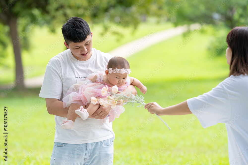 Fototapeta premium A Taiwanese couple in their 20s and their 7-month-old baby celebrate a birthday in a vast green park in Yilan County, Taiwan.