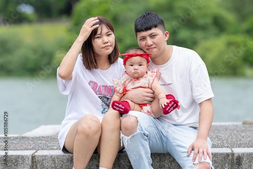 A Taiwanese couple in their 20s and their 7-month-old baby celebrate a birthday in a vast green park in Yilan County, Taiwan. photo