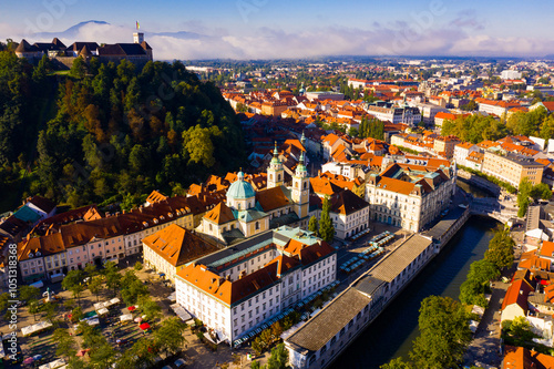 Aerial view of Slovenian town of Ljubljana overlooking fortified castle on hill and Roman Catholic Cathedral in morning sunlight photo