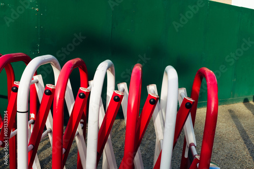 Red and white traffic barriers leaning on green wall