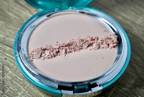 Round compact powder with scratch damage line isolated on horizontal ratio brown wooden table surface background. photo