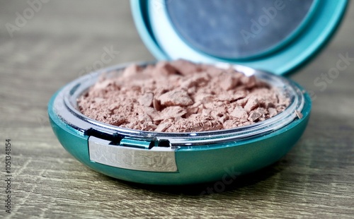 Crushed destroyed compact powder in round box container isolated on horizontal ratio brown wooden table surface background. photo