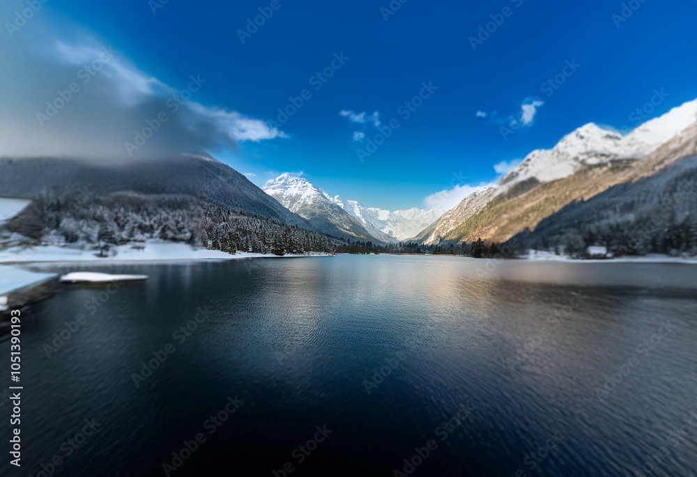 Obraz premium A serene mountain lake with snow-capped peaks reflecting in the still water.