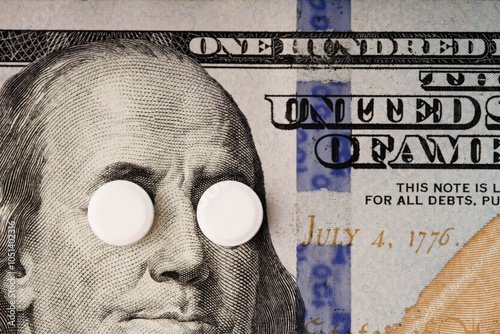 Obraz na płótnie High cost of medications concept . White pills covers Franklin's eyes on a banknote of 100 US dollars. w salonie