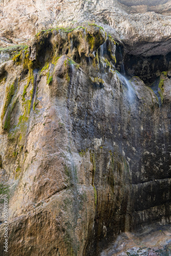 Fragment of falling streams of multi-level main waterfall Chegem with stone ledges/ Transparent water falls in several cascades from height of 60 meters, raising cloud of tiny water particles into air photo