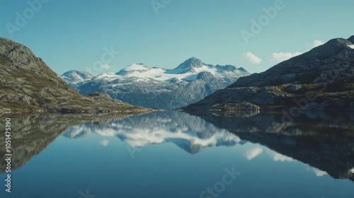 A sweeping mountain landscape with snow-capped peaks and a clear blue sky, a tranquil lake reflecting the entire scene.