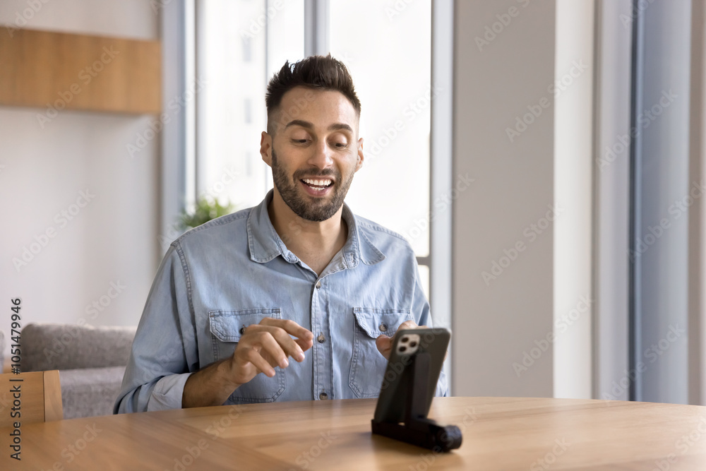 Fototapeta premium Happy Hispanic influencer man speaking at mobile phone web camera, giving business training, workshop, broadcasting on social media, blog on Internet, using phone on holder, talking on conference chat