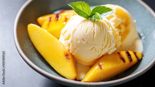 A scoop of ice cream served with grilled mango slices, offering a warm, caramelized fruit topping that contrasts with the cold dessert