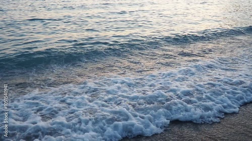 Waves gently lap at shore during stunning sunset over ocean. Golden sunlight reflects off waves as they roll onto shore, creating tranquil atmosphere at sunset by sea. Montenegro summer, Canj photo