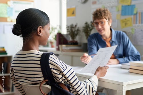 African American woman consulting with career advisor in office setting, engaging in conversation and holding document detailing potential opportunities photo