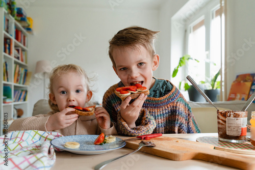 Brothers eating breads with sliced fruits at home photo