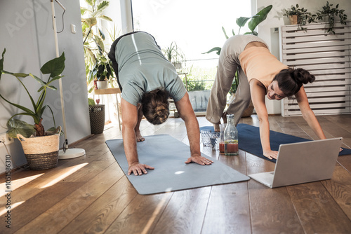 Young couple practicing downward facing dog position at home