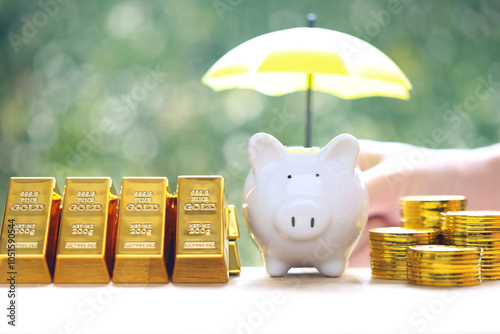 Protection, Gold bar and piggy bank with hand holding the umbrella on natural green background,Business investment and Saving money for prepare in future concept photo