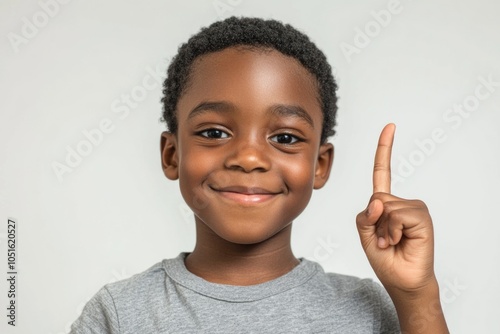 A young boy holds his index finger up in a gesture of victory or excitement