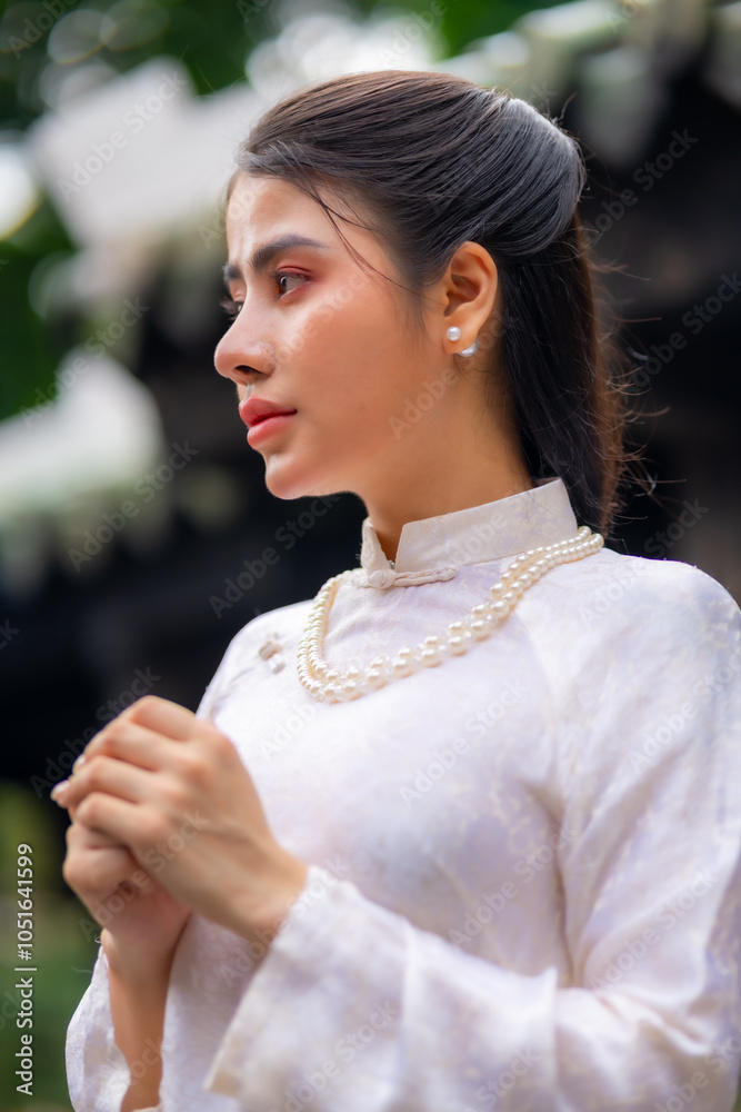 Vietnamese girl with Ao Dai dress standing in temple in Ho Chi Minh city, Vietnam. Ao dai is famous traditional costume for woman in Vietnam Vietnamese girl with Ao Dai dress standing in temple in Ho Chi Minh city, Vietnam. Ao dai is famous traditional costume for woman in Vietnam