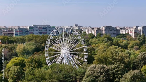 Rotating Drone View of a Ferris Wheel in Oraselul Copiilor Park with Apartment Buildings in the Background, Bucharest, Romania photo