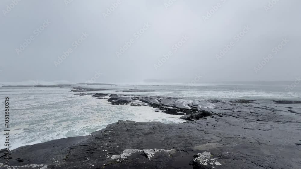 View in Kilkee, Ireland, during a storm in the Atlantic Ocean, choppy waves crash on rocks View in Kilkee, Ireland, during a storm in the Atlantic Ocean, choppy waves crash on rocks