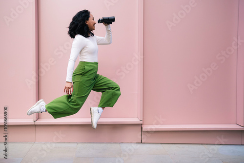 Carefree woman in mid-air looking through binoculars