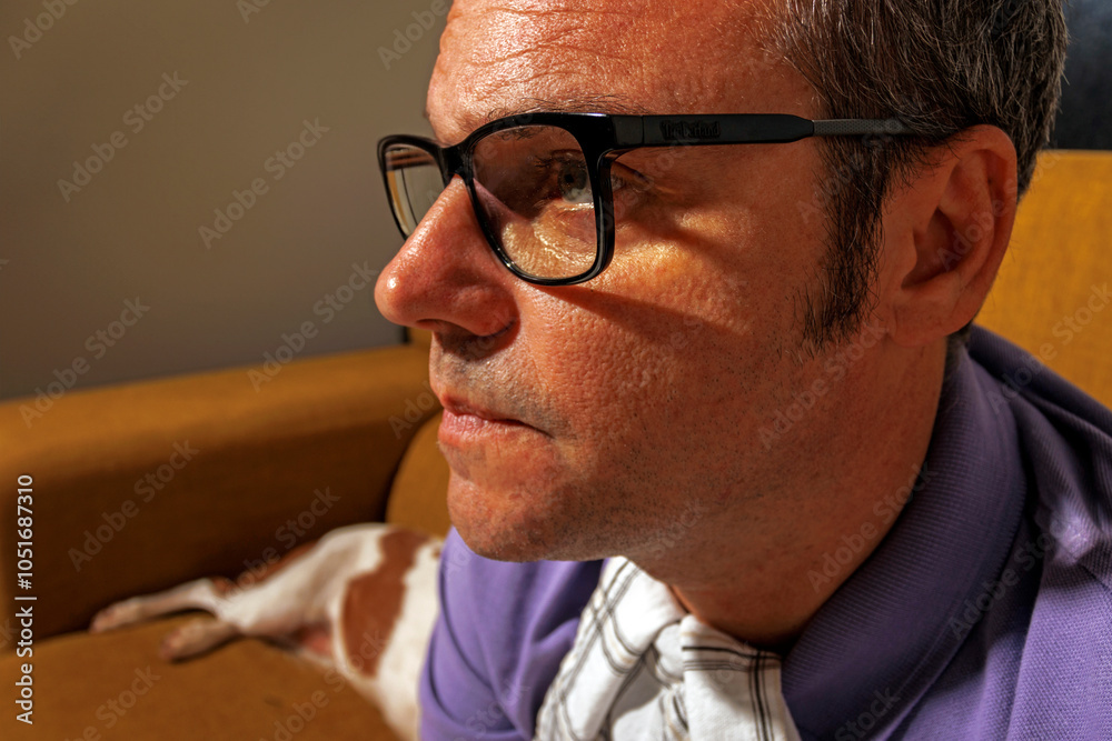 Mature man wearing eyeglasses and watching TV on sofa at home Mature man wearing eyeglasses and watching TV on sofa at home