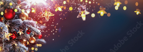Obraz na płótnie Christmas tree with Christmas balls on the background of the night sky - decorations on fir branches with shiny and unfocused lights and snowflakes on an abstract background w salonie