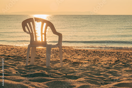 Fototapeta Naklejka Na Ścianę i Meble -  Broken plastic chair on a sandy beach in summer morning