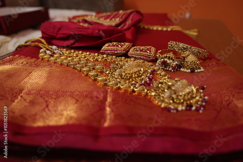 multiple gold chain and necklaces placed on red silk saree. indian Bridal gold jewelry collection. antique gold jewels