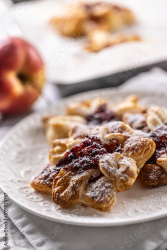 Sweet dessert pastries made of puff pastry with strawberry jam filled with caramelized apple sprinkled with powdered sugar