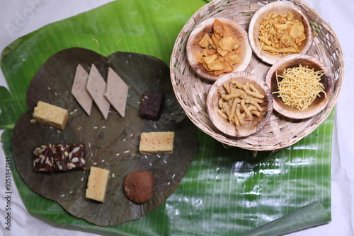 many types of indian sweets like kaj katli, halwa, badhusha and Mysore pak placed on a leaf photo