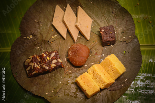 multiple milk flour south indian  sweets placed on banana leaf photo