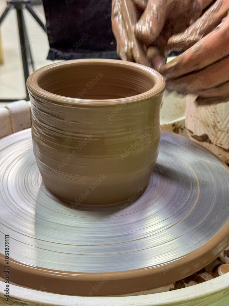 Handcrafting ceramics on a pottery wheel. Male hands shaping a clay object. Creativity, craftsmanship, and the art of pottery in motion