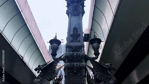 Historic street lanterns and detailed pillar stand beneath modern architecture in Nihonbashi Tokyo