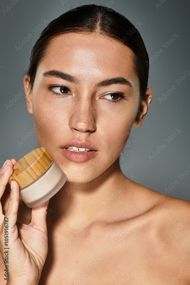 The woman displays a skincare product, radiating confidence and natural beauty. The woman displays a skincare product, radiating confidence and natural beauty.