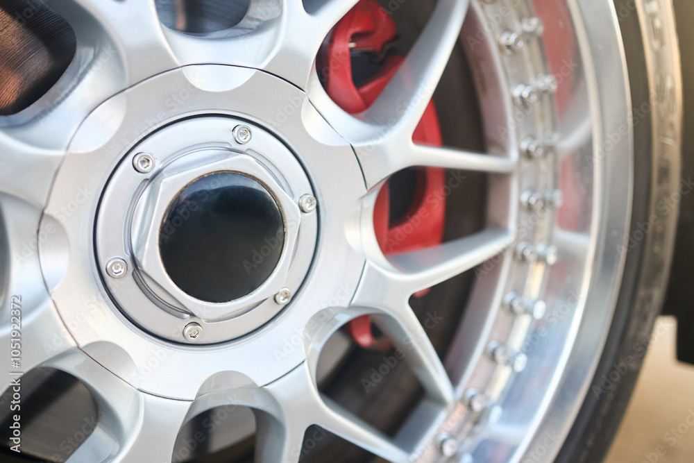 Obraz premium Alloy wheel rim plug and red brake caliper selective focus close up.