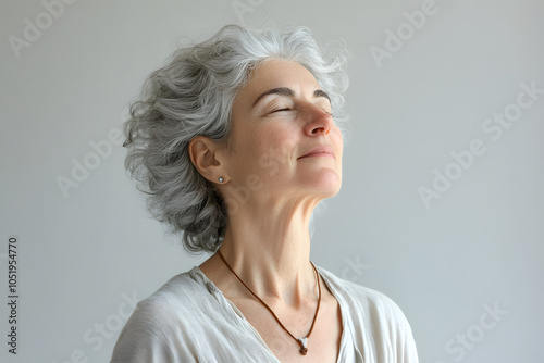 Portrait of a beautiful happy retired mature woman closing eyes and breathing deeply isolated on white background