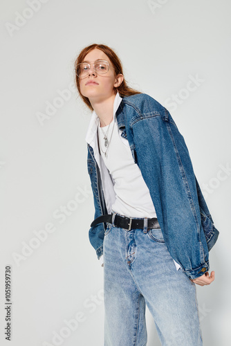 A young man with striking red hair showcases his denim style in a creative studio environment. photo