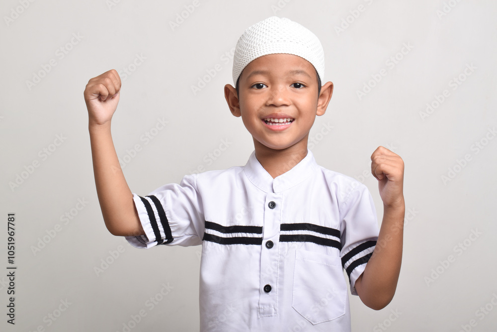 A happy and excited Muslim Asian boy with raised hands isolated on white background A happy and excited Muslim Asian boy with raised hands isolated on white background