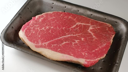 Beef steak in black plastic box tray.