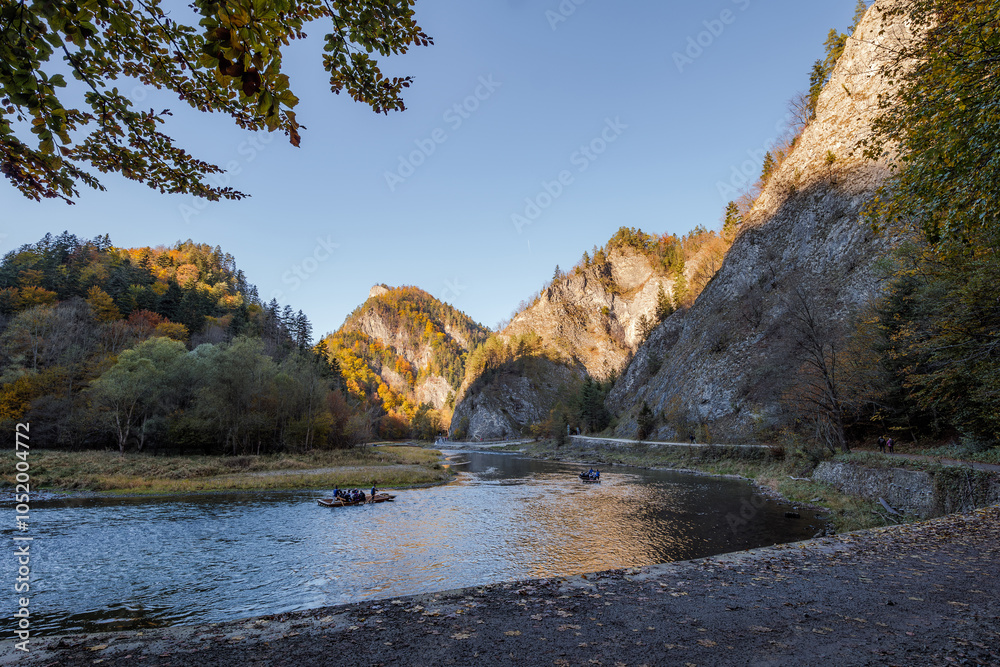 The gorge of the Dunajec River. Rafting down the river. The peaks illuminated by the afternoon sun. Mountains in autumn. Limestone rocks. Szczawnica, Poland