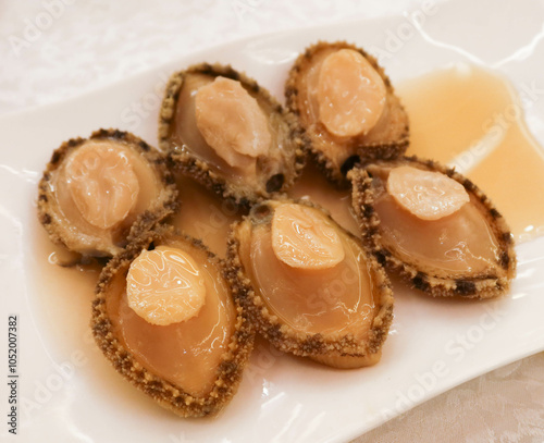 close up of six pieces of cold cut appetiser alcohol drunken abalone on a white plate