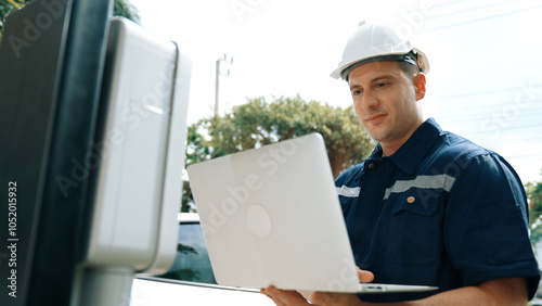 Qualified technician working on home EV charging station installation, making troubleshooting and configuration setup on charging system with laptop for EV at home. Synchronos