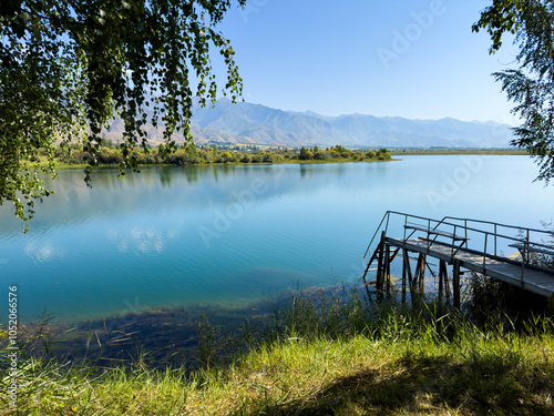 A wooden pier on Issyk-Kul lake with a view of the mountains. A beautiful spot for relaxation and enjoying the natural landscapes of Kyrgyzstan