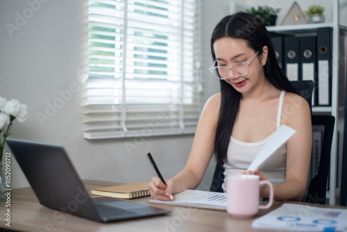 Asian accountant reviewing documents at home office desk Free Download Asian accountant reviewing documents at home office desk - GFXLoad