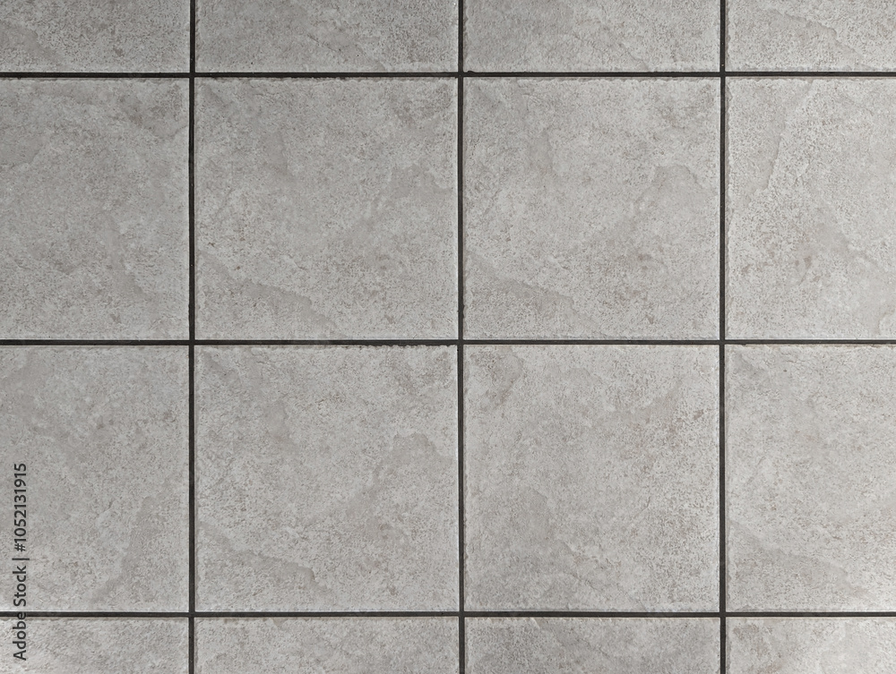 Naklejka premium Top view of interior and exterior textured ceramic floor with concrete or gray cement effect. Non-slip lihgt grey square bathroom, terrace, porch tiles with relief texture or background. 