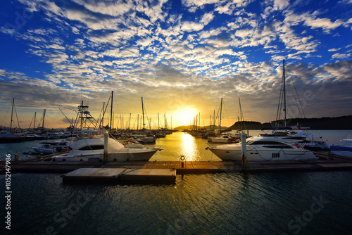 Landscape shot of  yacht harbour during the sunset with the beautiful clouds shape and color contrast of the blue anddyellow before twilight. photo