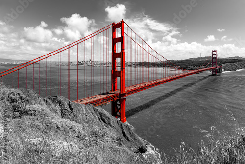 Wide angle panorama of world-famous Golden Gate Bridge, San Francisco, California. Black and white landscape and red steel construction of the suspension bridge spanning over the bay on a sunny day