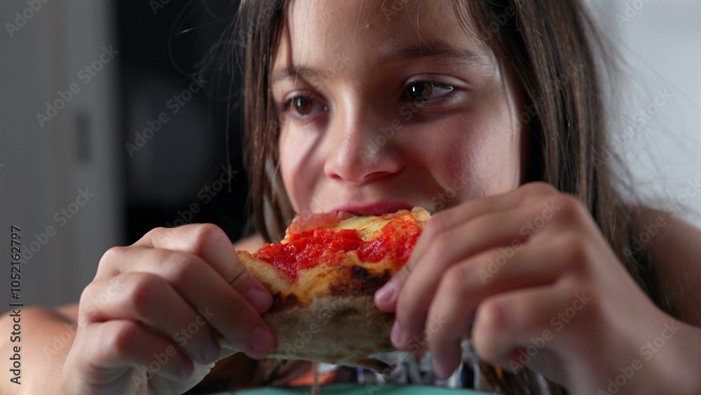Young girl holding a slice of pizza, looking intently at the food while sitting at a table indoors, capturing a moment of savoring her favorite dish in a close-up view Young girl holding a slice of pizza, looking intently at the food while sitting at a table indoors, capturing a moment of savoring her favorite dish in a close-up view