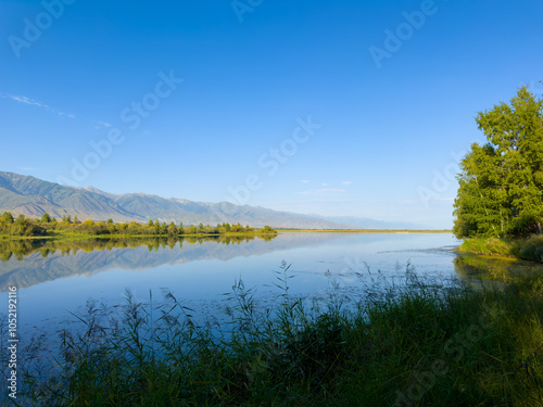 A wooden staircase leading into the clear waters of Issyk-Kul lake, with visible underwater vegetation. A perfect spot for water relaxation and enjoying nature